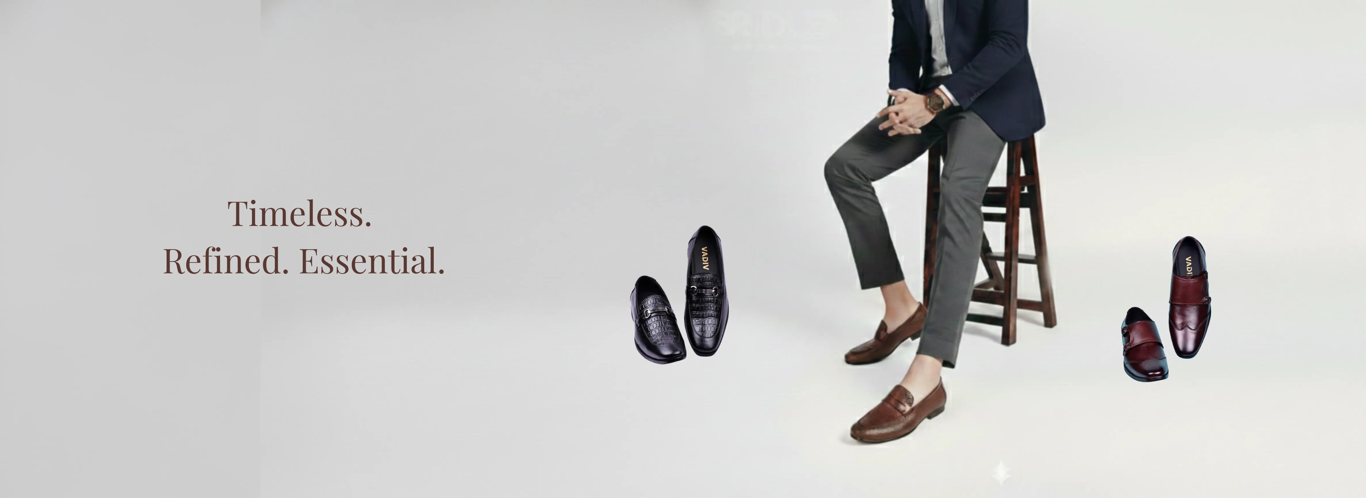Man sitting on a stool with shoes displayed around him, text 'Timeless. Refined. Essential.'